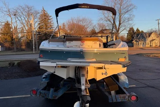 Slide: The Image of 2022 Cobalt CS22 boat on trailer, parked outdoors, showcasing rear view and swim platform. - 2