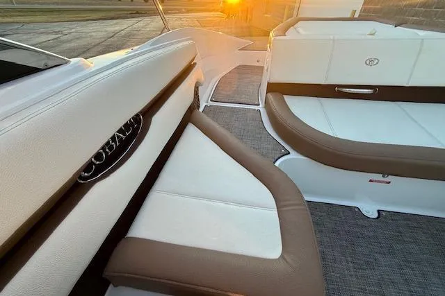 Slide: The Image of 2022 Cobalt CS22 boat interior with white and brown seating at sunset. - 33