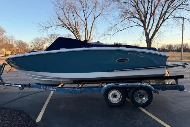 Slide: The Image of 2022 Cobalt CS22 boat on trailer, parked in a lot with trees in the background. - 7