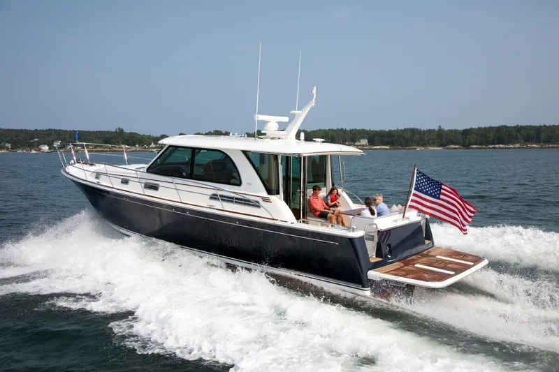 The Image of 2026 Sabre 45 Salon Express yacht cruising with passengers, American flag waving, scenic coastal backdrop. - 0