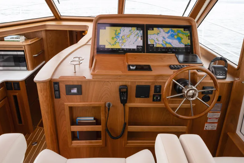 Slide: The Image of Interior helm of 2026 Sabre 45 Salon Express with dual navigation screens and wooden finish. - 12