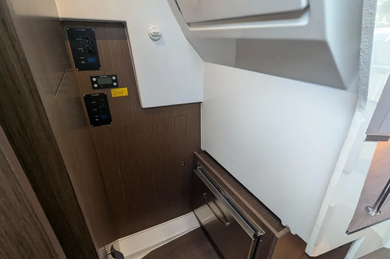 Slide: The Image of 2024 Beneteau Antares 11 interior with control panels and compact refrigerator. - 10
