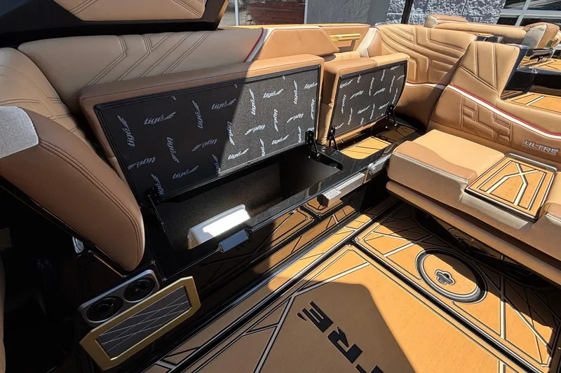 Slide: The Image of 2026 Tigé Ultré 25ZX boat interior with tan seating and storage compartments open. - 25