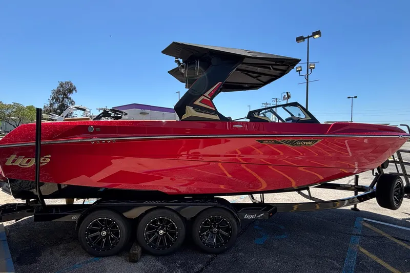 Slide: The Image of 2026 Tigé Ultré 25ZX boat in vibrant red on a trailer, parked outdoors. - 4