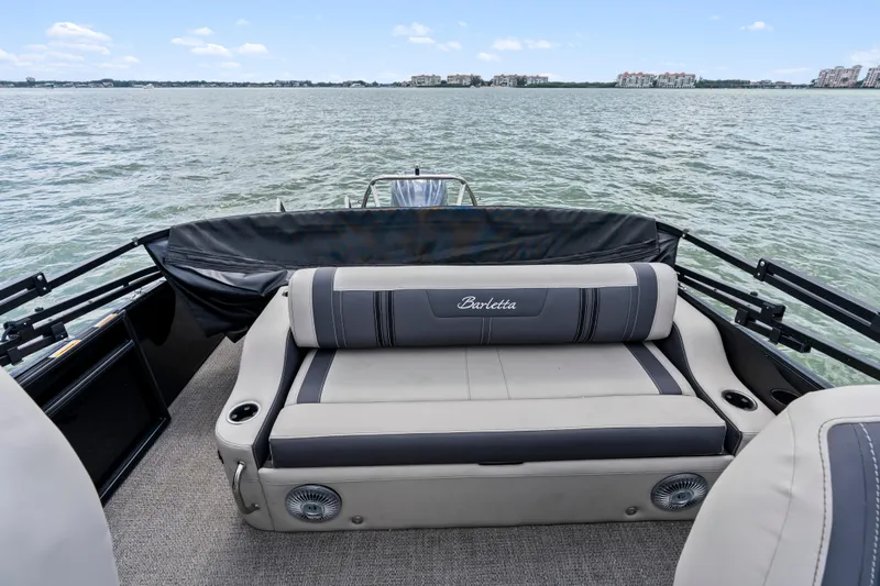Slide: The Image of 2025 Barletta Corsa 23UC pontoon boat interior with comfortable seating on a lake. - 13