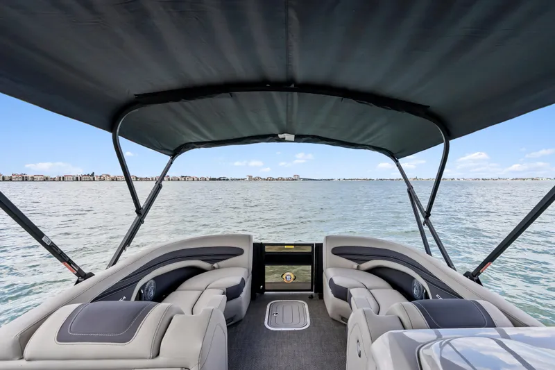 Slide: The Image of 2025 Barletta Corsa 23UC pontoon boat interior with canopy, overlooking serene water. - 16