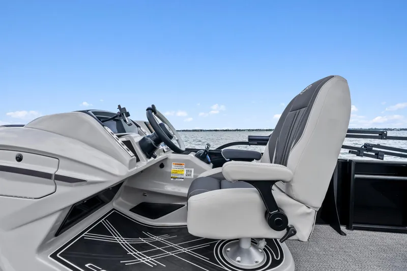 Slide: The Image of 2025 Barletta Corsa 23UC boat interior with captain's chair and steering wheel, on a calm lake. - 7