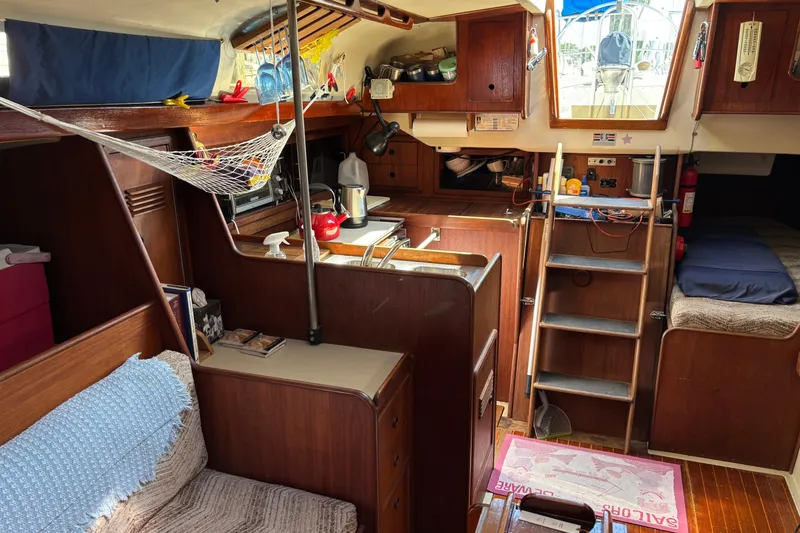 Slide: The Image of Interior of a 1980 C&C 40-2 sailboat, featuring a cozy kitchen and wooden furnishings. - 16