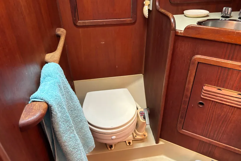 Slide: The Image of Wooden boat bathroom with toilet and sink, featuring a blue towel. C&C 40-2, 1980 model. - 20
