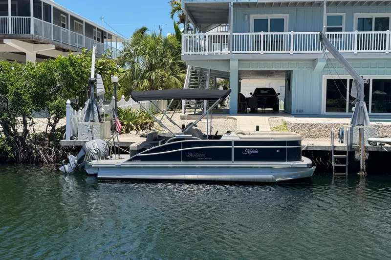 The Image of 2021 Barletta C20UC pontoon boat docked by a waterfront house. - 0