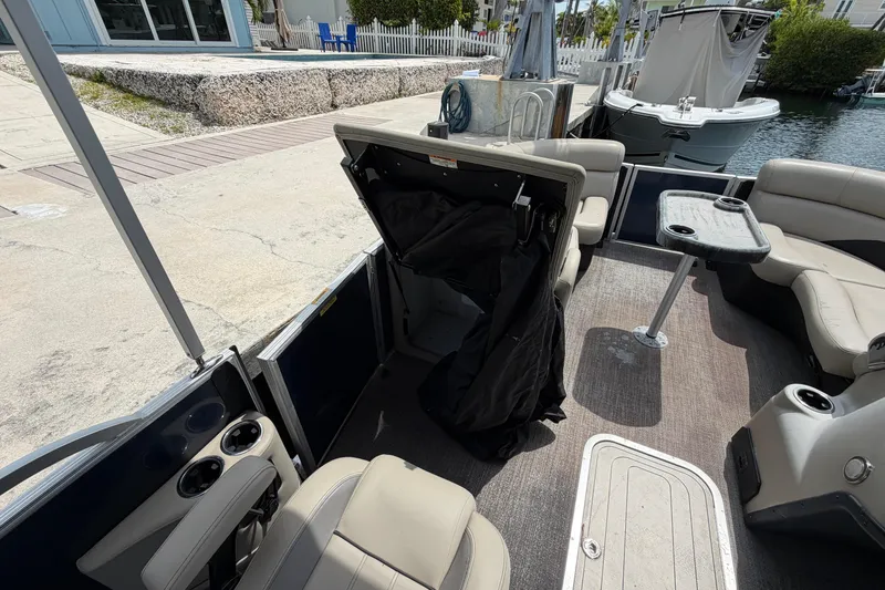 Slide: The Image of 2021 Barletta C20UC pontoon boat interior with seating and table, docked by the water. - 10