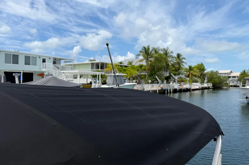 Slide: The Image of 2021 Barletta C20UC boat with black canopy near waterfront homes and palm trees. - 16