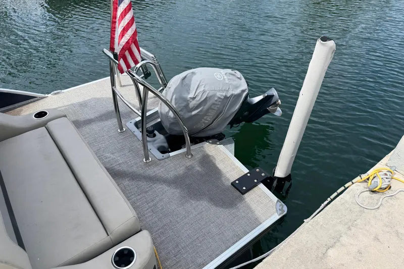 Slide: The Image of 2021 Barletta C20UC pontoon boat with covered motor and American flag at dock. - 17