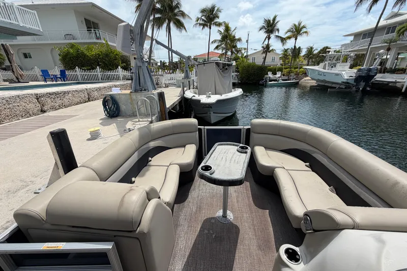 Slide: The Image of 2021 Barletta C20UC pontoon boat with beige seating docked by waterfront homes. - 3