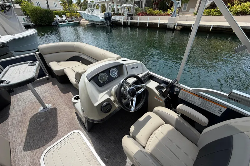 Slide: The Image of 2021 Barletta C20UC pontoon boat interior with steering console and seating by the water. - 4
