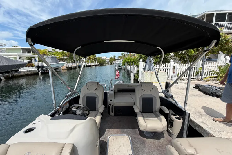 Slide: The Image of 2021 Barletta C20UC pontoon boat with canopy, docked by a scenic waterfront. - 5