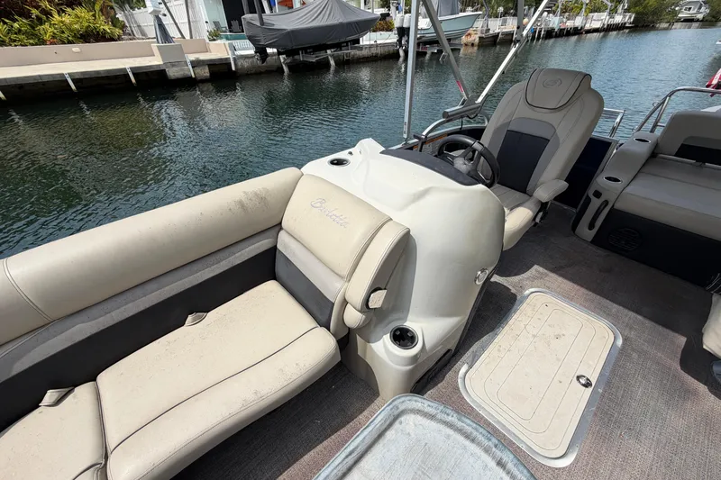 Slide: The Image of 2021 Barletta C20UC pontoon boat interior with beige seating and steering console by a canal. - 6