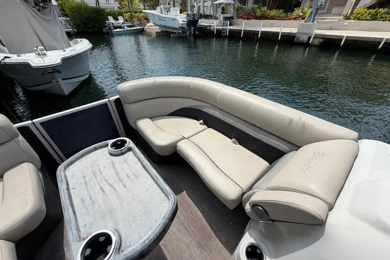 Slide: The Image of 2021 Barletta C20UC pontoon boat interior with seating and table, docked by the water. - 7