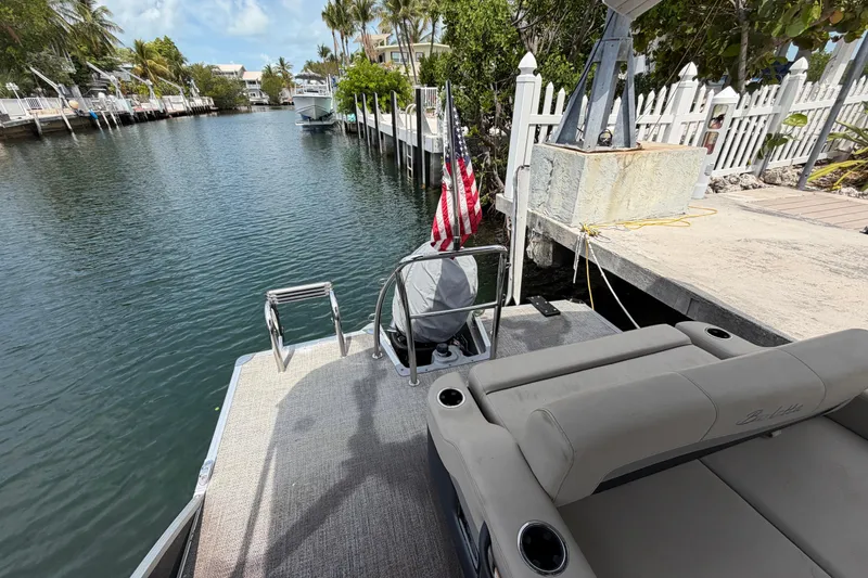 Slide: The Image of 2021 Barletta C20UC pontoon boat docked by a scenic canal with lush greenery. - 9