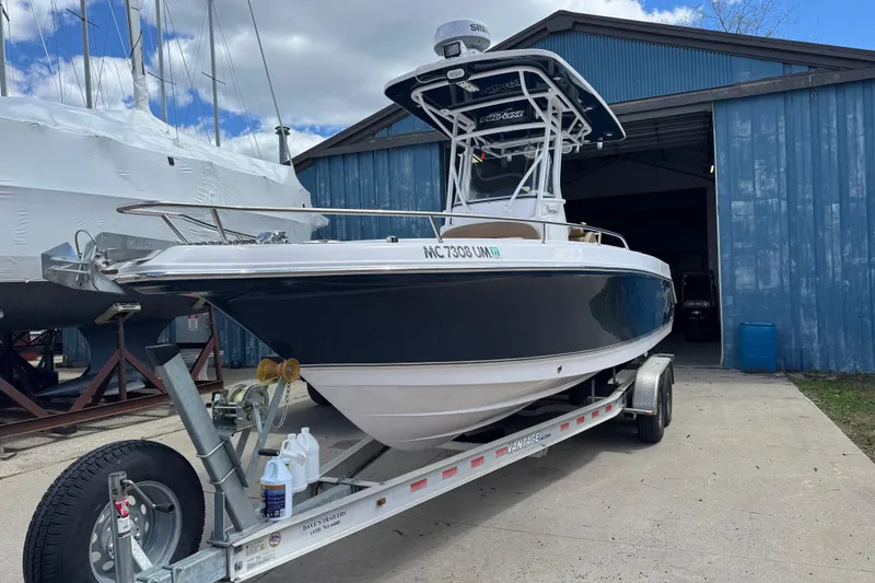Slide: The Image of 2017 Pro-Line 26 Super Sport boat on trailer outside blue storage building. - 1