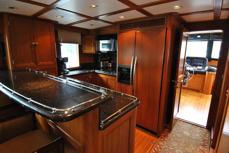 Slide: The Image of Luxurious 2002 Grand Alaskan Cockpit Motor Yacht kitchen with wood cabinetry and modern appliances. - 13