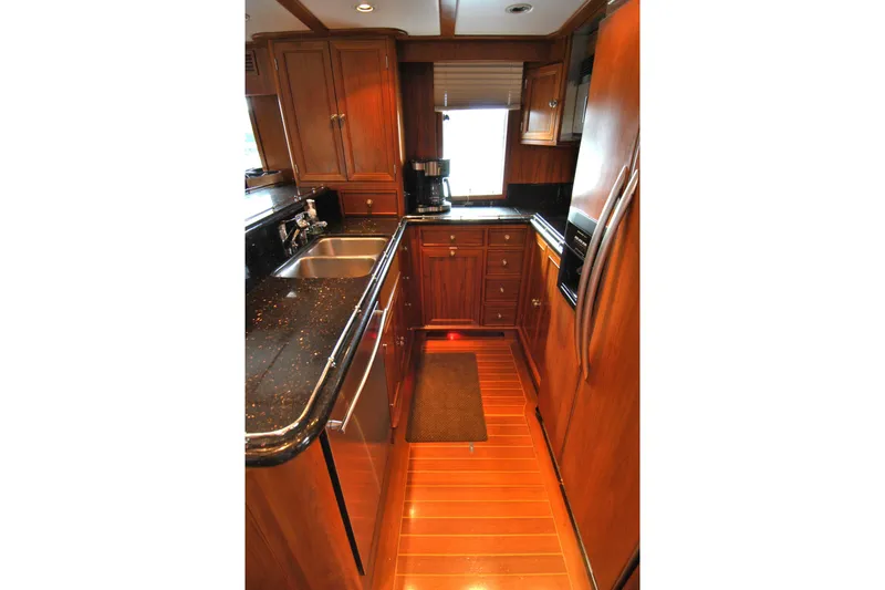 Slide: The Image of Luxurious kitchen interior of 2002 Grand Alaskan Cockpit Motor Yacht with wood cabinetry and modern appliances. - 14