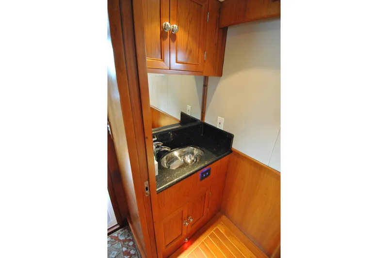 Slide: The Image of 2002 Grand Alaskan Cockpit Motor Yacht interior with wooden cabinetry and compact sink area. - 18