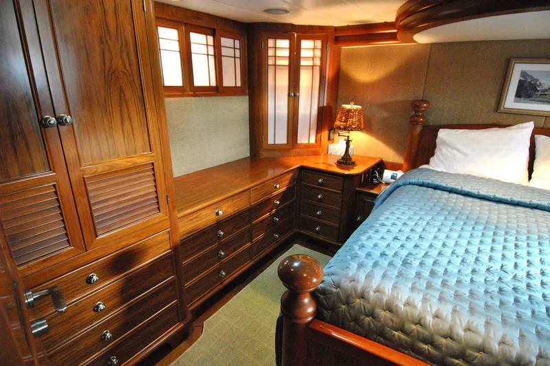 Slide: The Image of Luxurious 2002 Grand Alaskan Cockpit Motor Yacht bedroom with elegant wood cabinetry and cozy bedding. - 26
