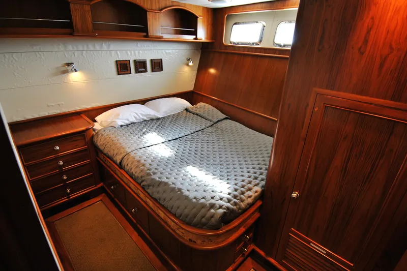 Slide: The Image of Luxurious wood-paneled bedroom in 2002 Grand Alaskan Cockpit Motor Yacht, featuring cozy bedding and elegant design. - 29