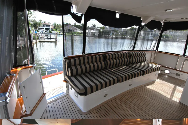 Slide: The Image of 2002 Grand Alaskan Cockpit Motor Yacht with striped seating, docked by a serene waterfront. - 5