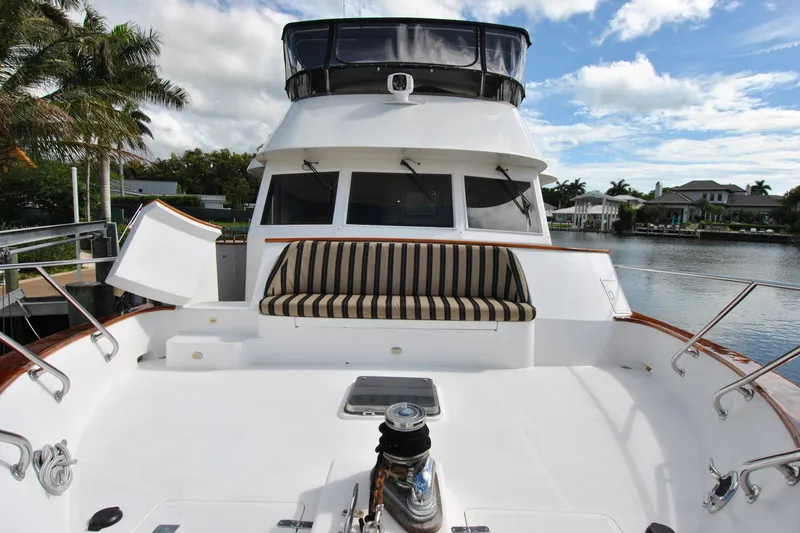 Slide: The Image of 2002 Grand Alaskan Cockpit Motor Yacht with striped seating, docked by palm trees and waterfront homes. - 53