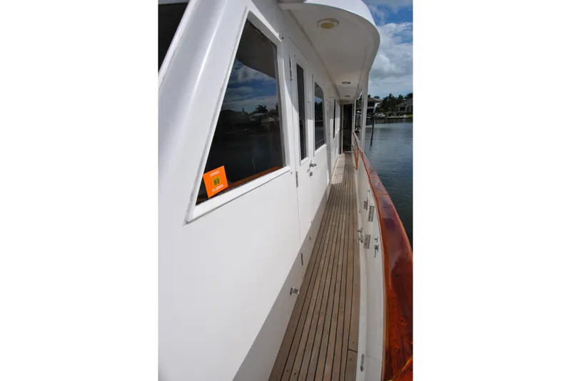 Slide: The Image of 2002 Grand Alaskan Cockpit Motor Yacht deck with wooden flooring and sleek white exterior. - 54