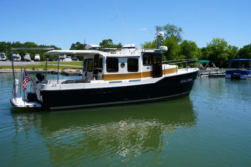 The Image of 2014 Ranger Tugs R-31 boat docked on a sunny day with lush greenery. - 1