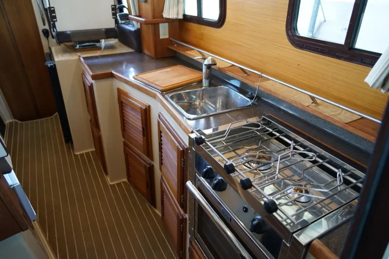 Slide: The Image of 2014 Ranger Tugs R-31 galley with stove, sink, and wooden cabinetry. - 28