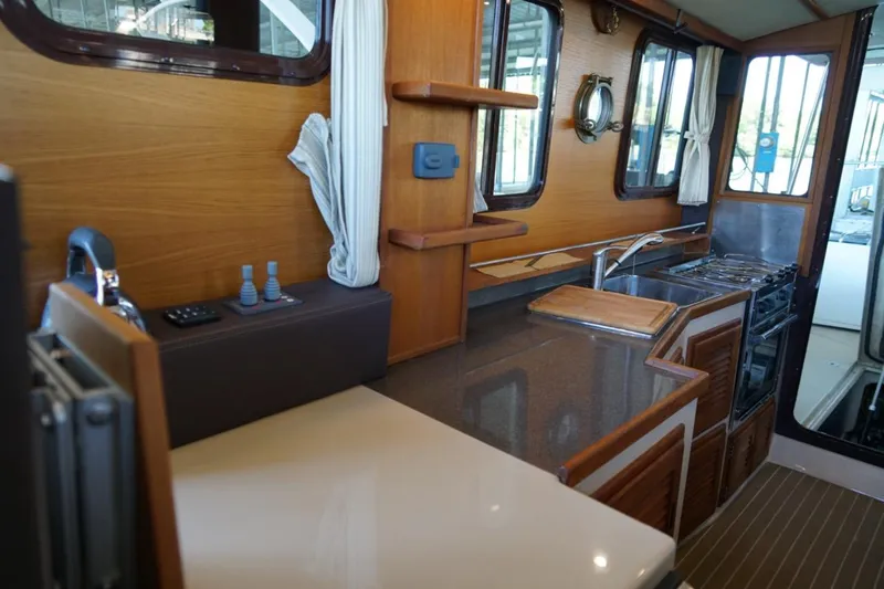 Slide: The Image of Interior of 2014 Ranger Tugs R-31, featuring a compact kitchen with wood accents. - 34