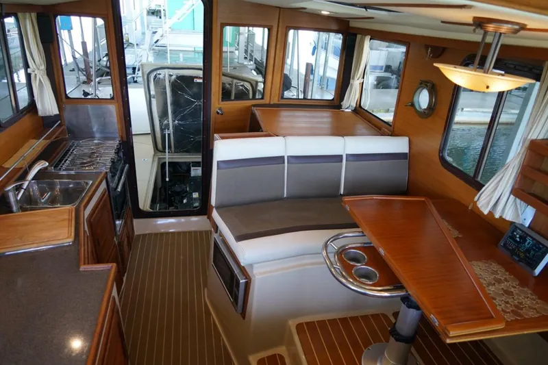 Slide: The Image of 2014 Ranger Tugs R-31 interior with kitchen, seating, and wooden table. - 36