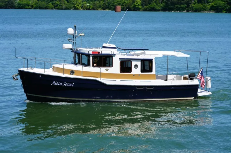 Slide: The Image of 2014 Ranger Tugs R-31 boat named "Aleta Jewel" cruising on a serene lake. - 5
