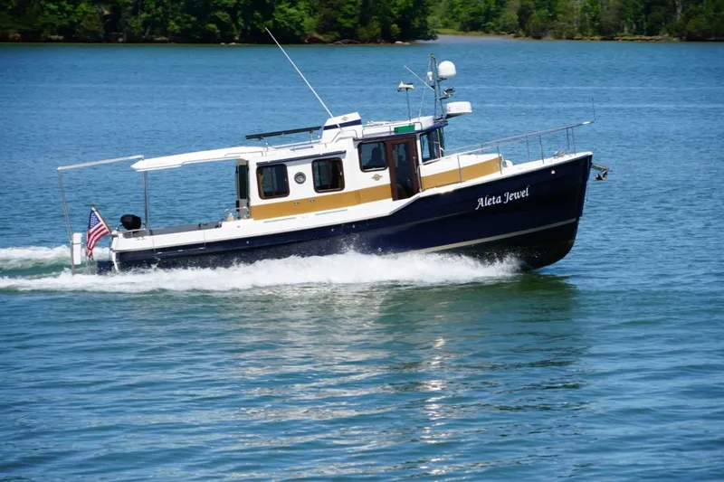 Slide: The Image of 2014 Ranger Tugs R-31 boat cruising on a serene lake with lush green shoreline. - 6
