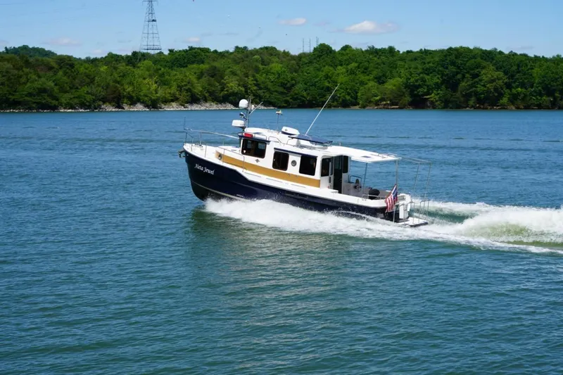 Slide: The Image of 2014 Ranger Tugs R-31 cruising on a scenic lake with lush green shoreline. - 8