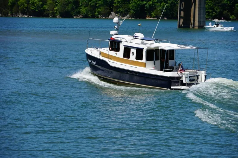 Slide: The Image of 2014 Ranger Tugs R-31 cruising on a scenic lake with lush green shoreline. - 9