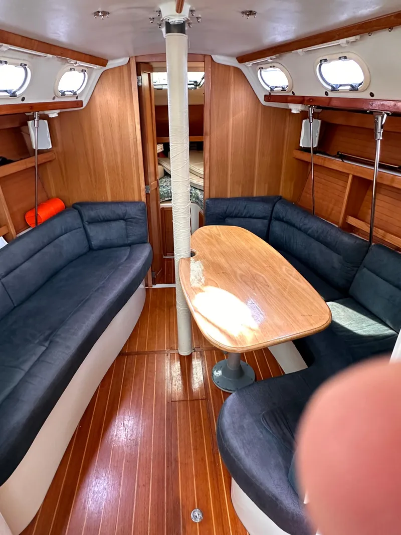 Slide: The Image of Interior of a 2000 Catalina 320 sailboat with wooden table and seating. - 2