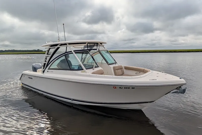 Slide: The Image of 2011 Pursuit DC 265 Dual Console boat on calm water under cloudy skies. - 1