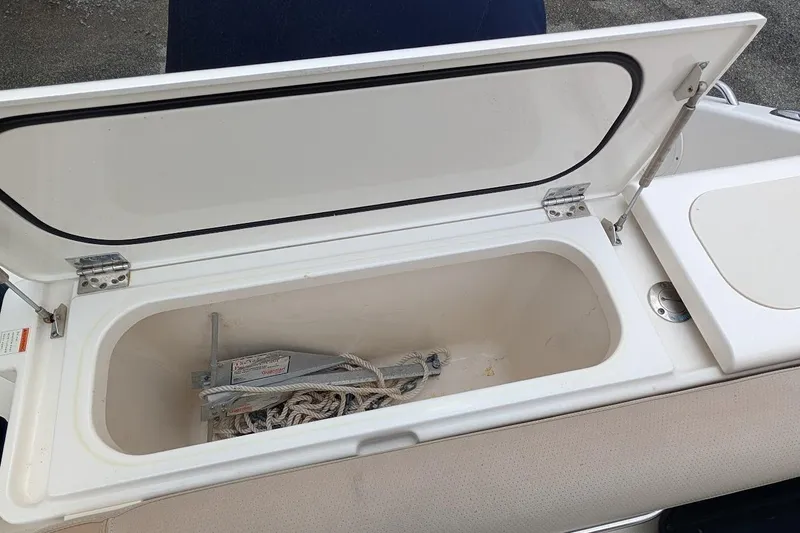 Slide: The Image of Open storage compartment on 2011 Pursuit DC 265 Dual Console boat, containing anchor and rope. - 10