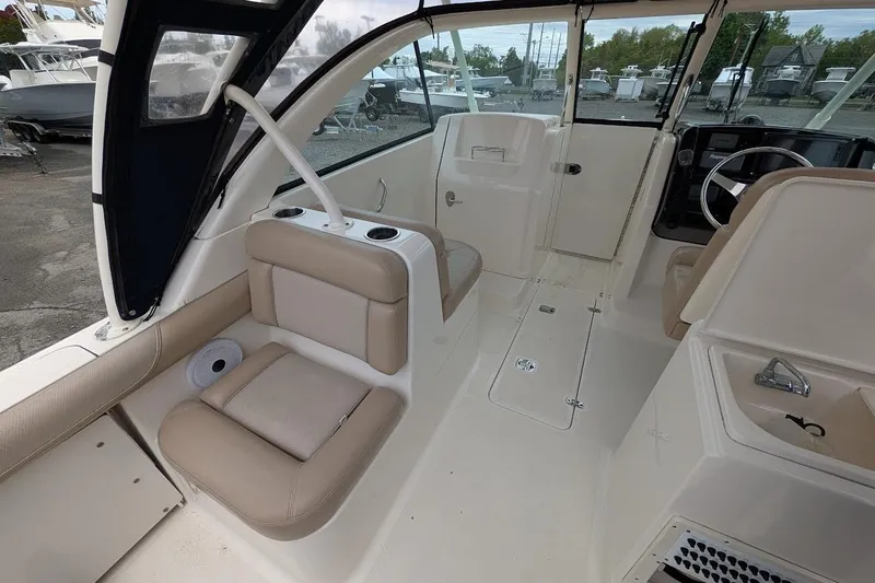 Slide: The Image of 2011 Pursuit DC 265 Dual Console boat interior with beige seating and steering wheel. - 16