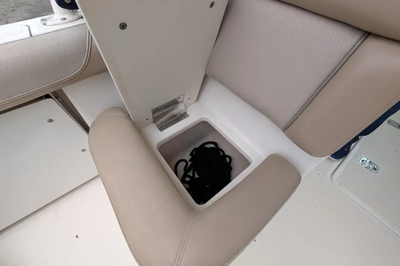 Slide: The Image of 2011 Pursuit DC 265 Dual Console boat seat storage compartment with rope. - 17