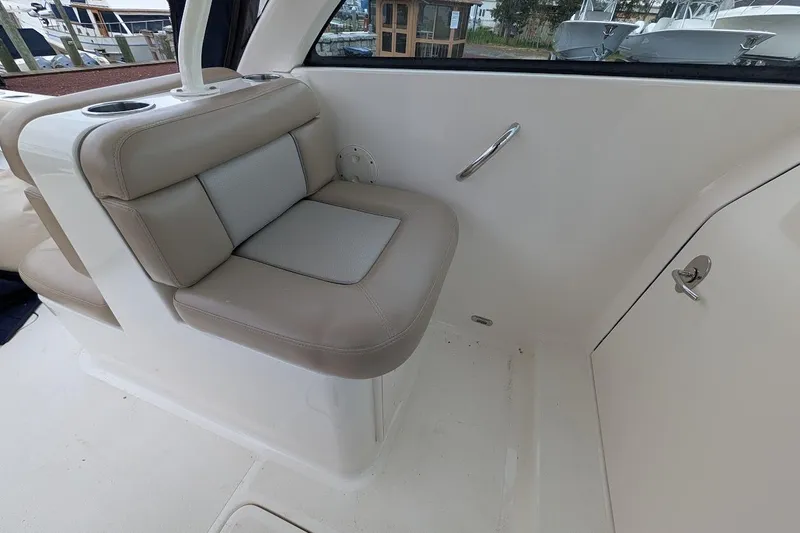 Slide: The Image of 2011 Pursuit DC 265 Dual Console boat interior with beige seating and cup holder. - 18