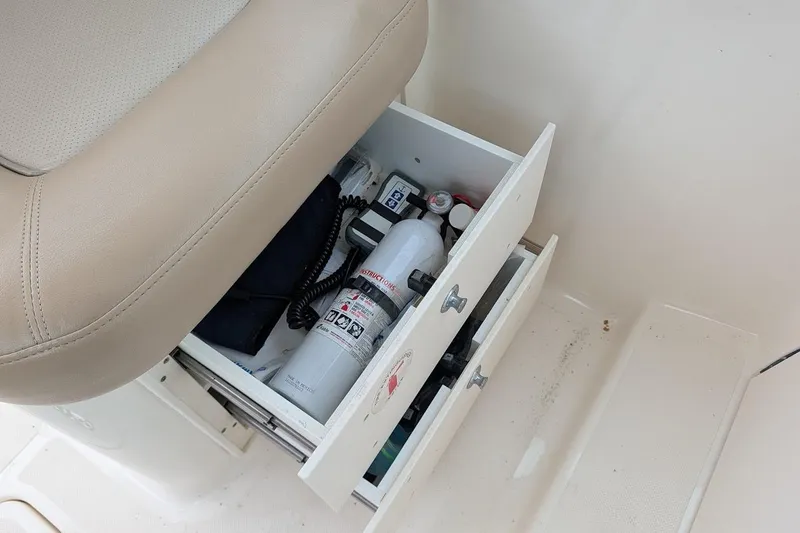 Slide: The Image of Storage compartment in a 2011 Pursuit DC 265 Dual Console boat with safety equipment. - 19