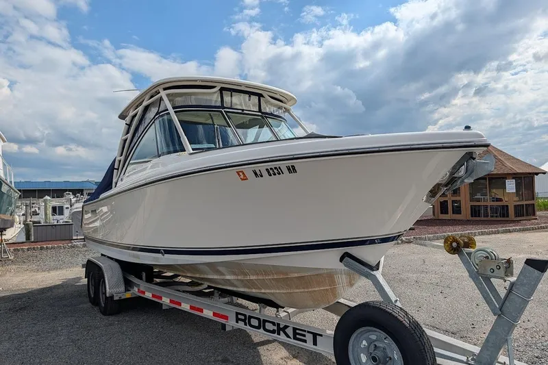 Slide: The Image of 2011 Pursuit DC 265 Dual Console boat on trailer under cloudy sky. - 2
