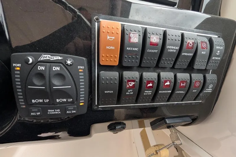 Slide: The Image of Control panel of a 2011 Pursuit DC 265 Dual Console boat with various switches and buttons. - 22