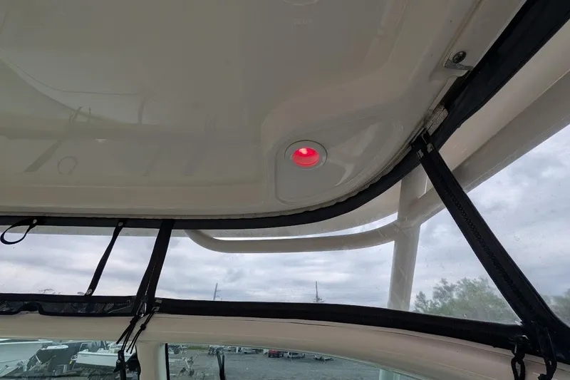Slide: The Image of 2011 Pursuit DC 265 Dual Console boat interior with red cabin light and clear canopy. - 26